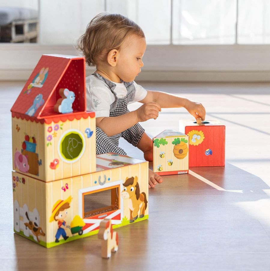Brinquedo educativo casa de madeira Goula - à venda na americana Criança a brincar com uma casa de madeira da marca Goula.