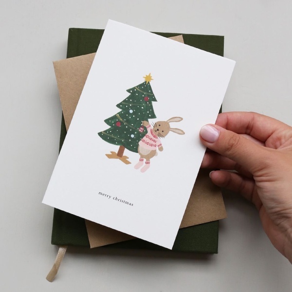 postal kartotek com árvore de natal e coelho com texto "Merry Christmas"